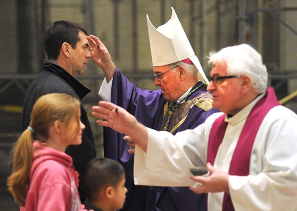 Flanked by Rev. Msgr. David S. Slubecky, Vicar General, Bishop Richard J. Malone distributes ashes at the 12:05 p.m. Mass at St. Joseph Cathedral. (Dan Cappellazzo/Staff Photographer )